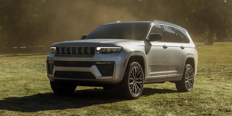 Front-view of a 2026 Jeep Grand Cherokee from Gray CDJR, idle in the middle of a grass field.